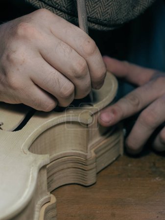 Foto de Primer plano del maestro profesional luthier luthier minucioso trabajo detallado sobre violín de madera en un taller. - Imagen libre de derechos