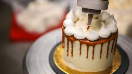 Téléchargez les photos : Chef décorant le haut d'un gâteau à la crème au beurre givré - en image libre de droit