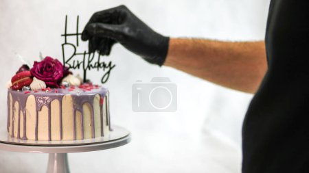 Photo for Chef usign macaron , flowers and text sign for a celebration cake - Royalty Free Image