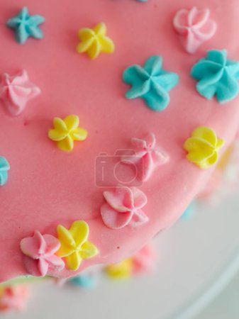 Photo for Close up of pink frosted dripping cake with donut and plastel brushed royal star sprinkles insolated on white studio shot - Royalty Free Image