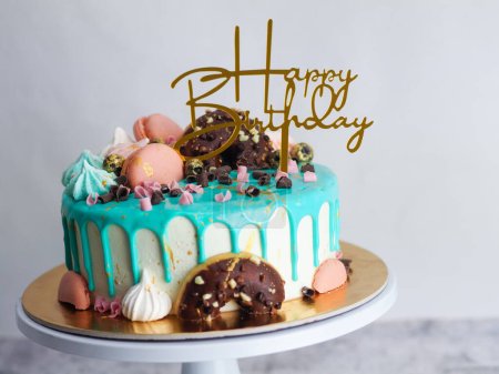 Photo for Donuts meringue berries and sparkles topping on frosted icing drip turquoise cake for birthday celebration - Royalty Free Image