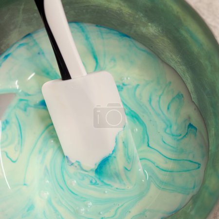 Photo for Pastry chef stirring piping bag filling mixed with edible turquoise paint for color grading frosted cake topping - Royalty Free Image