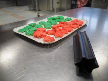 Foto de Panadero chef rebanando rojo violeta amarillo y verde estrella y corazón en forma de bollos de color en la cocina de catering - Imagen libre de derechos