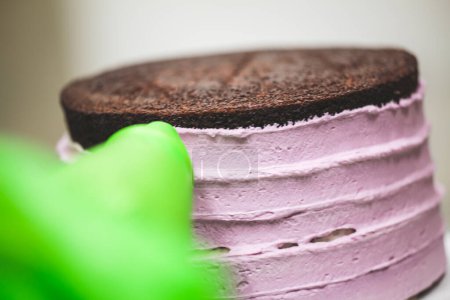Photo for Cake chef designer using rose cream filling piping bag decorating layered dark chocolate cake at kitchen lab - Royalty Free Image