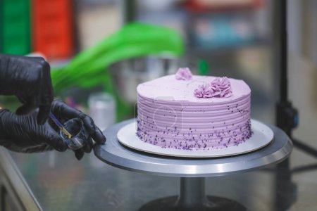 Téléchargez les photos : Pâtissier artisan peinture avec peinture comestible noire un gâteau texturé élégant givré lilas - en image libre de droit