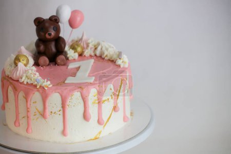 frosted dripping icing pink white cake with handmade bear topping on stand on white background for one year old baby girl