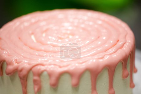 Photo for Cake chef designer preparing a pink dripping on white frosted cake for baby girl birthday celebration at kitchen lab - Royalty Free Image