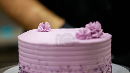Téléchargez les photos : Gâteau chef designer en utilisant la crème rose remplissage sur le gâteau lilas chocolat givré en couches au laboratoire de cuisine - en image libre de droit