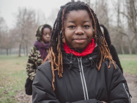 Photo for A happy young black girl walk with mother in a park in cold weather wearing sportswear.Afro dreadlock hairstyle. - Royalty Free Image