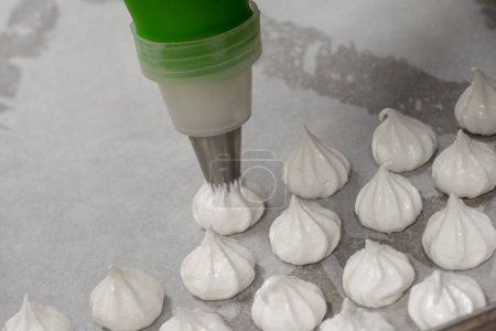 Photo for Pastry chef baker artisan making white swirl and twirl meringue cones with piping bag filled with egg cream and sugar to bake for sweet preparation - Royalty Free Image