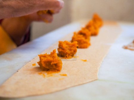 Photo for Senior woman preparing stuffed pumpkin ravioli tortelli with wholewheat italian grain flour at home, homemade food concept - Royalty Free Image