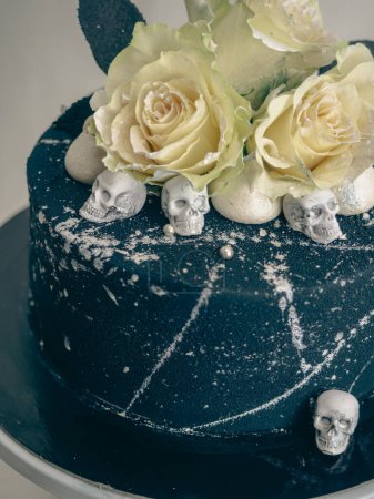 Photo for Birthday black airbrush painted frosted icing cake, two real roses silver sprayed and edible chocolate skull toppers and silver brush strokes - Royalty Free Image