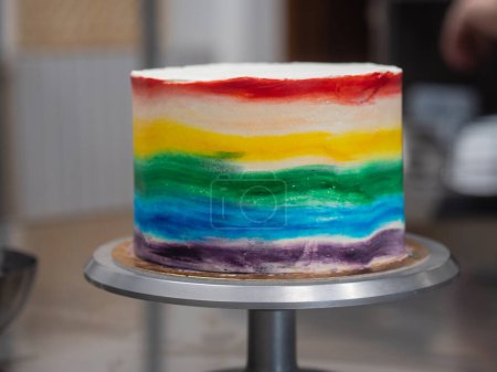 Photo for Pastry chef working on a frosted cup cake with lgbt rainbow colours for wedding union party celebration. Birthday cupcake. Rainbow paper cup liners. Happy Birthday. Celebration Holidays. LGBT pride. - Royalty Free Image