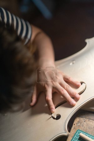Foto de Luthier fabricante de violín de trabajo, recorte y corte f agujeros en una mesa de violín superior en el taller - Imagen libre de derechos
