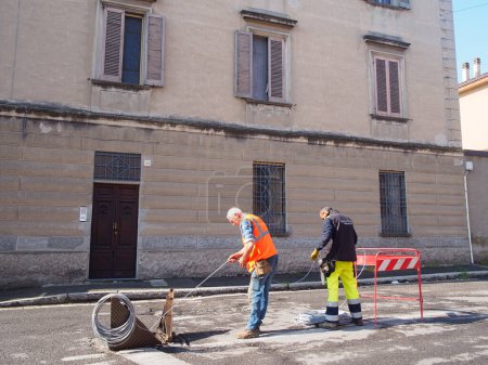 Photo for Cremona, Lombardy - May 2023 Internet, phone lines , fiber optic speedy connection installing in old cities. The cable is fed through from long spool. Install conduit for fiber optic cable. - Royalty Free Image