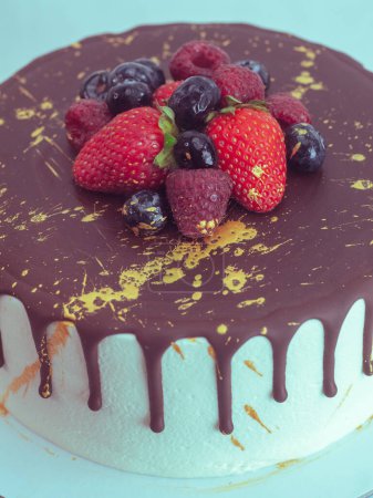 Photo for Frosted icing cake , chocolate covered, strawberry and blueberry topping, golden paint splash for a special celebration - Royalty Free Image