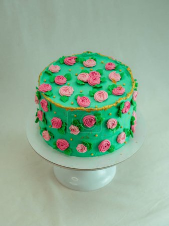Photo for Green icing frosted cake with sugar paste roses and pearls topping decoration all around the shape isolated on studio - Royalty Free Image