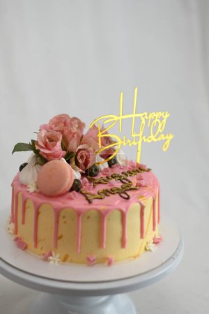 Foto de Glaseado fresco goteando rosa pastel de vainilla de cumpleaños rosas reales y decoración de macaron en la parte superior con signo de oro - Imagen libre de derechos