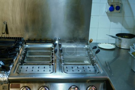 Koch lässt Pasta aus professionellem Boiler in Küchenrestaurant in Italien abtropfen