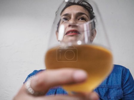 Photo for Woman sommelier evaluating white wine at a cozy restaurant, exuding enjoyment and expertise. Perfect for celebrations or aperitifs. Cheers to wine lovers everywhere. - Royalty Free Image