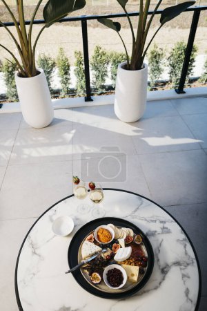 Foto de Quesos, salsas, frutas y bebidas en el balcón con interiores modernos - Imagen libre de derechos