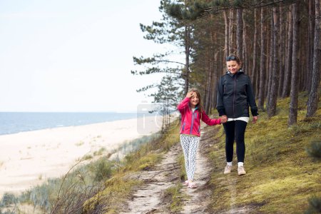 Foto de Mujer y su hija caminando por la orilla del mar y el bosque. Vacaciones familiares en el mar. Viaje de verano. Disfrutando del tiempo libre. Tiempo libre cerca de la naturaleza. Concepto de viaje - Imagen libre de derechos