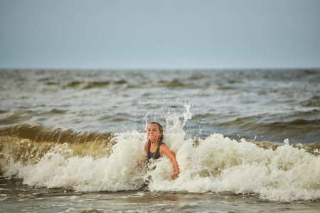 Foto de Niña jugando con olas en el mar. Chico salpicando juguetonamente en olas. Niño saltando en el mar. Vacaciones en la playa. Salpicaduras de agua. Diversión y juego durante las vacaciones de verano. Concepto de viaje - Imagen libre de derechos