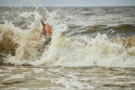Foto de Niña jugando con olas en el mar. Chico salpicando juguetonamente en olas. Niño saltando en el mar. Vacaciones en la playa. Salpicaduras de agua. Diversión y juego durante las vacaciones de verano. Concepto de viaje - Imagen libre de derechos