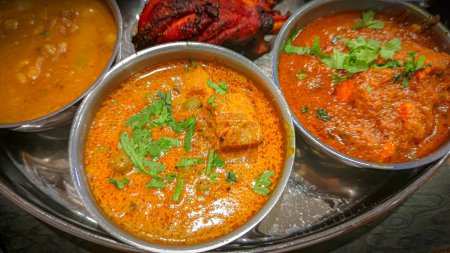 Traditionelle indische Küche. Verschiedene indische Speisen auf dem Tisch im Restaurant. Vorspeisen und Gerichte der indischen Küche. Curry, Reis, Samosa, Naan, Butterhuhn, Chutney, Gewürze, Palak Paneer, Tikka, Roti
