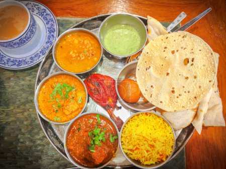 Foto de Cocina tradicional india. Surtido de comida india en la mesa en el restaurante. aperitivos y platos de cocina india. Curry, arroz, samosa, naan, mantequilla de pollo, chutney, especias, Palak Paneer, Tikka, Roti - Imagen libre de derechos