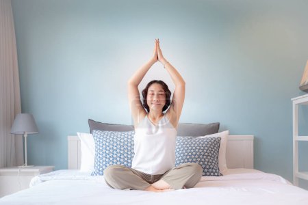 Téléchargez les photos : Femme asiatique pratiquant un cours de yoga à la maison. Asiatique femme au foyer passe-temps Formation en ligne pratiquant yoga, respiration, méditation souriant détendu, pour le bien-être, bien-être - en image libre de droit