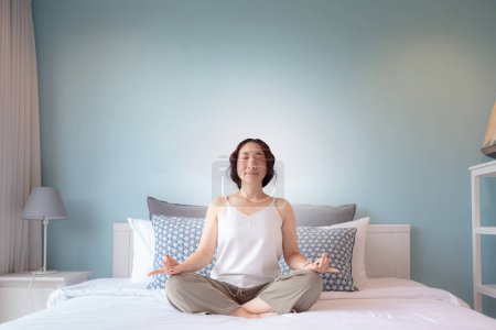 Photo for Asian woman practicing yoga lesson at home. Asian woman housewife's hobby Online training practicing yoga , breathing, meditating smiling relaxed, for Well being, wellness - Royalty Free Image