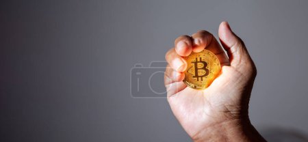 Téléchargez les photos : La main des personnes âgées tient une pièce d'or Bitcoin. La monnaie crypto-monnaie Confiance financière des personnes âgées après la retraite concept. - en image libre de droit