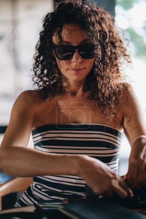 Téléchargez les photos : Portrait d'une femme bouclée dans des lunettes de soleil. Photo de haute qualité - en image libre de droit