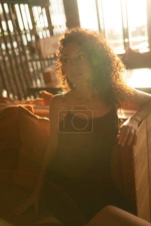 Foto de Retrato de una mujer rizada sentada en retroiluminación. Foto de alta calidad - Imagen libre de derechos