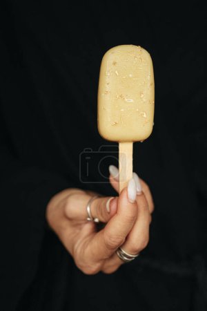 mano femenina está sosteniendo un helado esquimal en el fondo oscuro. Foto de alta calidad