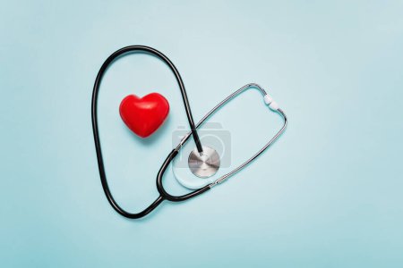 stethoscope with its tubing creating heart shape around red heart model on Pale Blue Background symbolizing love and care in the medical field.