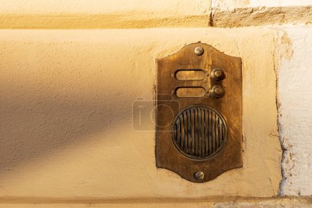 Photo for Close-up of a brass intercom with two doorbells on a yellow and white wall  with copy space, Italy, Europe. - Royalty Free Image