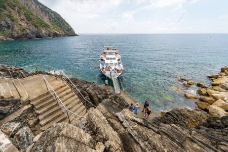 Photo for RIOMAGGIORE, ITALY - JULY 8, 2021: Tourist ferry to the Cinque Terre National Park docked in front of the small village of Riomaggiore, La Spezia, Italy, Europe. UNESCO world heritage site. - Royalty Free Image