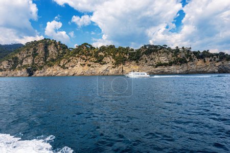 Photo for Ferry with tourists in motion from Portofino to San Fruttuoso bay, tourist resorts in Genoa Province, Liguria, Italy, Europe. Rocky coastline and Mediterranean sea. - Royalty Free Image