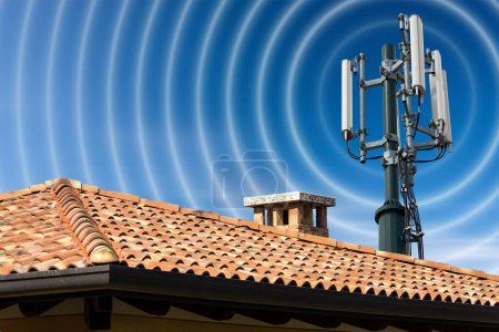 Photo for Closeup of a house roof with a telecommunications tower with antennas (aerial) and radio waves, against a clear blue sky with clouds and copy space. - Royalty Free Image