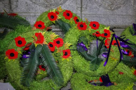 Foto de Wreath - remembrance day in memory of soldiers who died in wars. Red poppy flowers on green grass background - Imagen libre de derechos