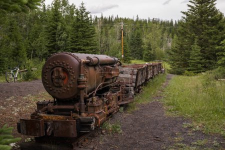 Viejo tren oxidado - locomotora de vapor. Una mina de carbón abandonada cubierta de bosque en las montañas. Un lugar místico.