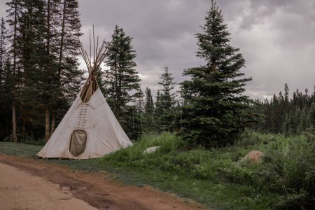 Téléchargez les photos : Une tente tipi wigwam se tient seule dans la forêt. Loisirs actifs en montagne. Randonnée pédestre, camping, abri dans les Rocheuses, Alberta, Canada - en image libre de droit