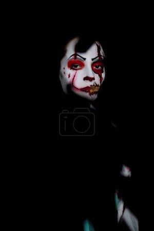 Téléchargez les photos : Portrait de jeune femme en image zombie sanguinaire avec des blessures horribles sur le visage sur fond noir. Image effrayante pour Halloween. - en image libre de droit