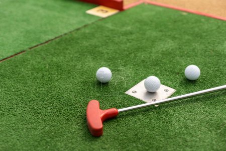 Foto de Assorted miniature golf putters and balls askew on synthetic grass - Imagen libre de derechos