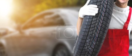Téléchargez les photos : Changeur de pneu mâle En cours de vérification de l'état des pneus neufs qui sont en stock à remplacer dans un centre de service ou un atelier de réparation automobile Dépôt de pneus pour l'industrie automobile - en image libre de droit