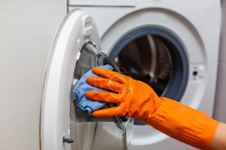 Photo for A man in yellow gloves cleans a dirty, moldy rubber seal on a washing machine. Mold, dirt, limescale in the washing machine. Periodic maintenance of household appliances - Royalty Free Image