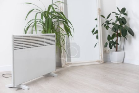 plant and electric heating battery on a gray background, harm dry air for houseplants concept, heating season.