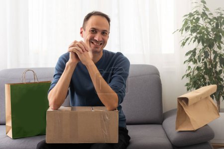 Foto de Post, hogar y concepto de estilo de vida - hombre sonriente con cajas de cartón en casa - Imagen libre de derechos